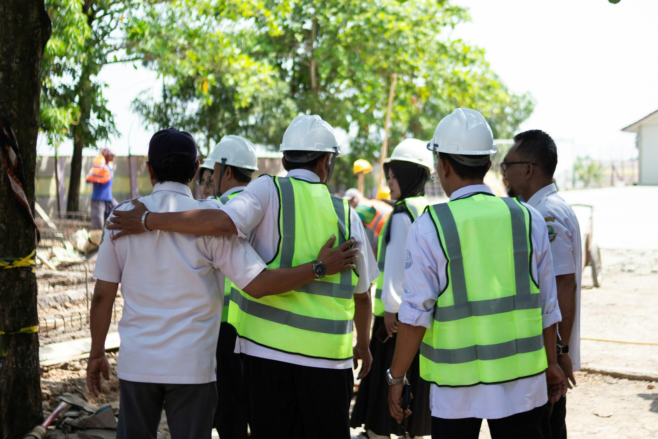 Site staff wearing hard hats and high-visibility vests gathered outdoors